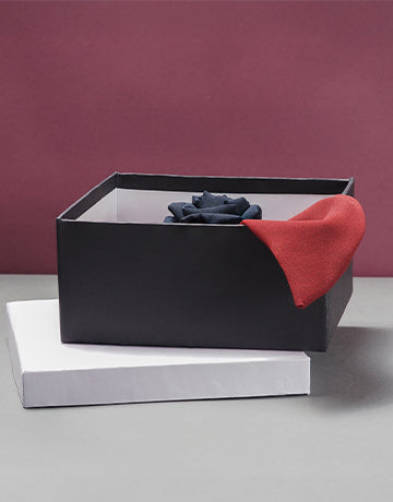 Black gift box with a handmade silk rose hair clip in black and red, displayed on a white box with a soft burgundy background
