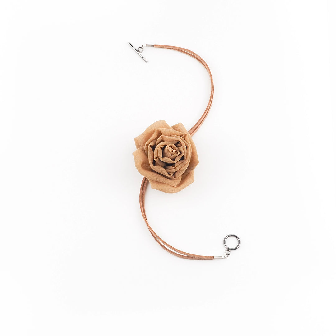 Flat lay of handcrafted gold silk rose choker with suede lace and toggle clasp displayed on white background
