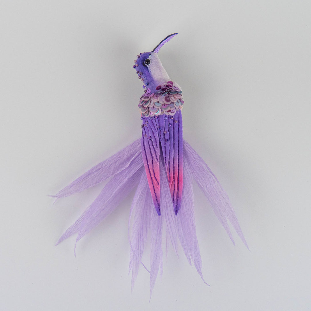 Front view of a handmade purple and white hummingbird brooch, embroidered with silk and chiffon, statement textile accessory made in UK