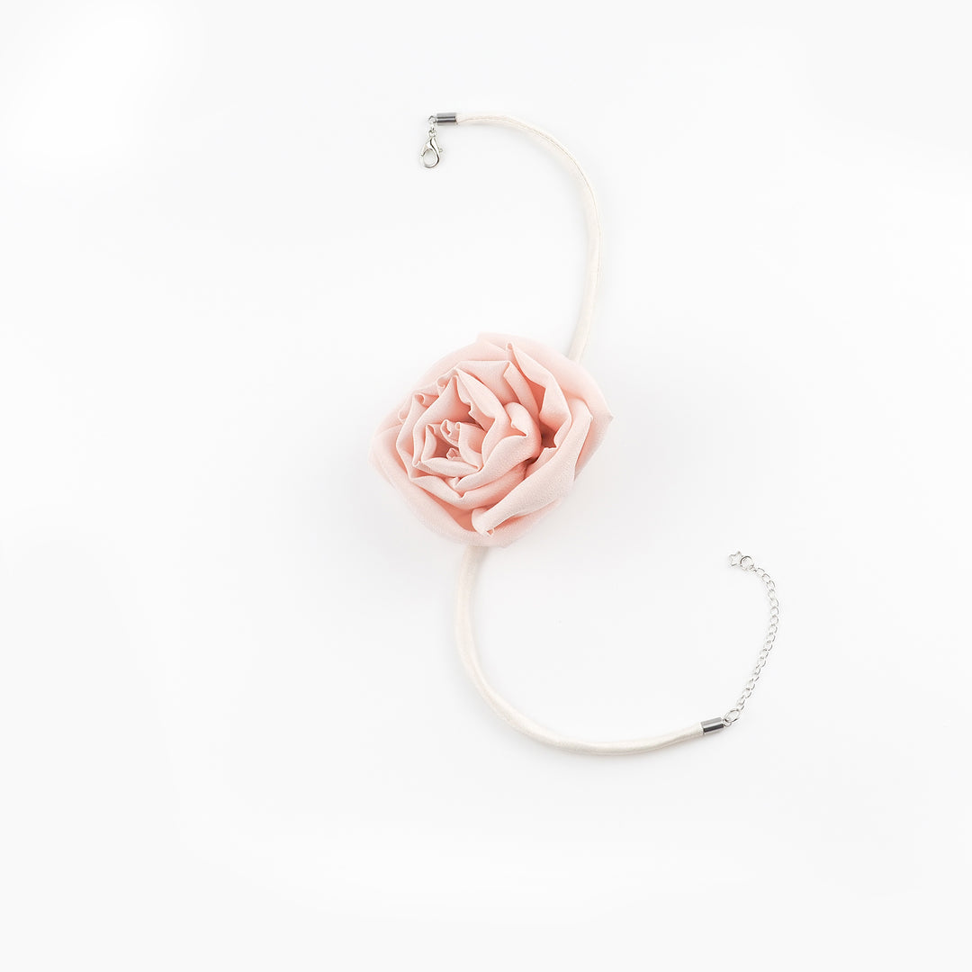 Flat lay of the Pink Silk Rose Choker Necklace showing a blush-pink silk rose centerpiece, dupioni silk band, and silver lobster clasp with star charm chain