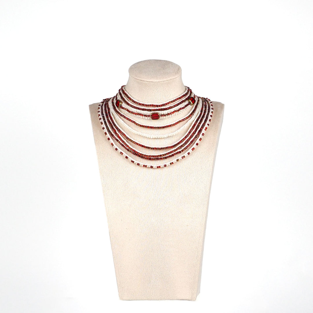 Handmade red and white multi-strand necklace with glass beads, mother of pearl beads, and larger gold-edged round beads, displayed on a mannequin bust
