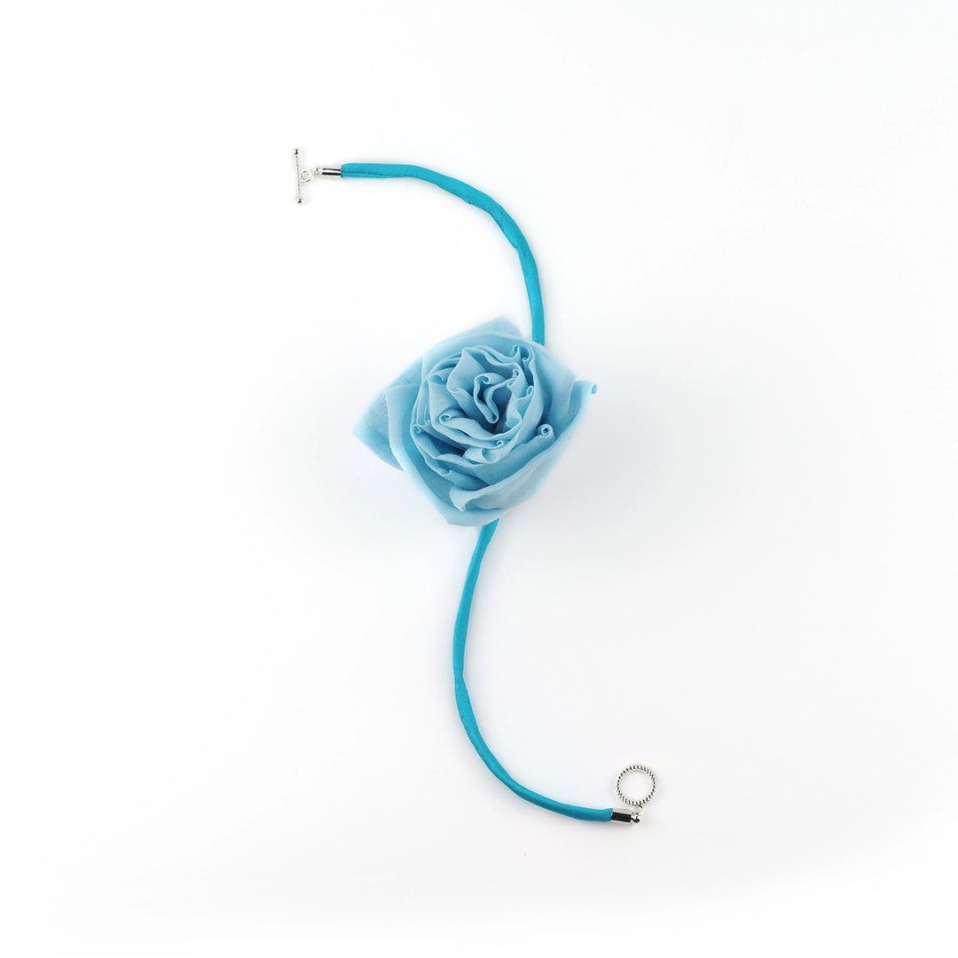 Flat lay of blue silk rose choker showing adjustable rose and open toggle clasp