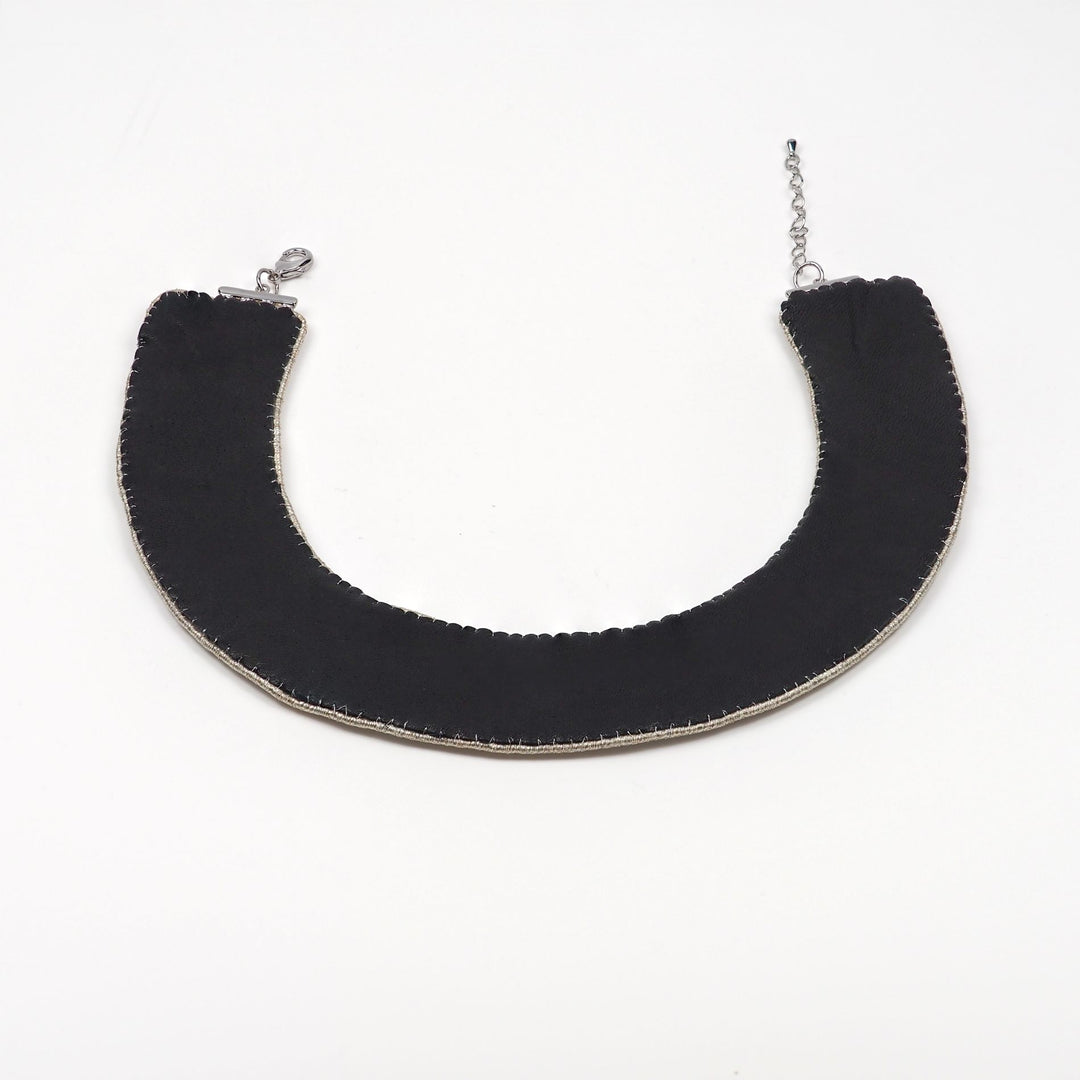 Back view of a handmade black collar necklace with smooth leather backing, hand-stitched edges, and adjustable lobster clasp fastening.