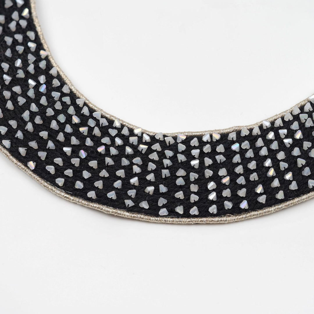 Close-up of pearl-tone cut beads with angular shapes, hand-set using a traditional pearl setting technique on a black collar necklace.