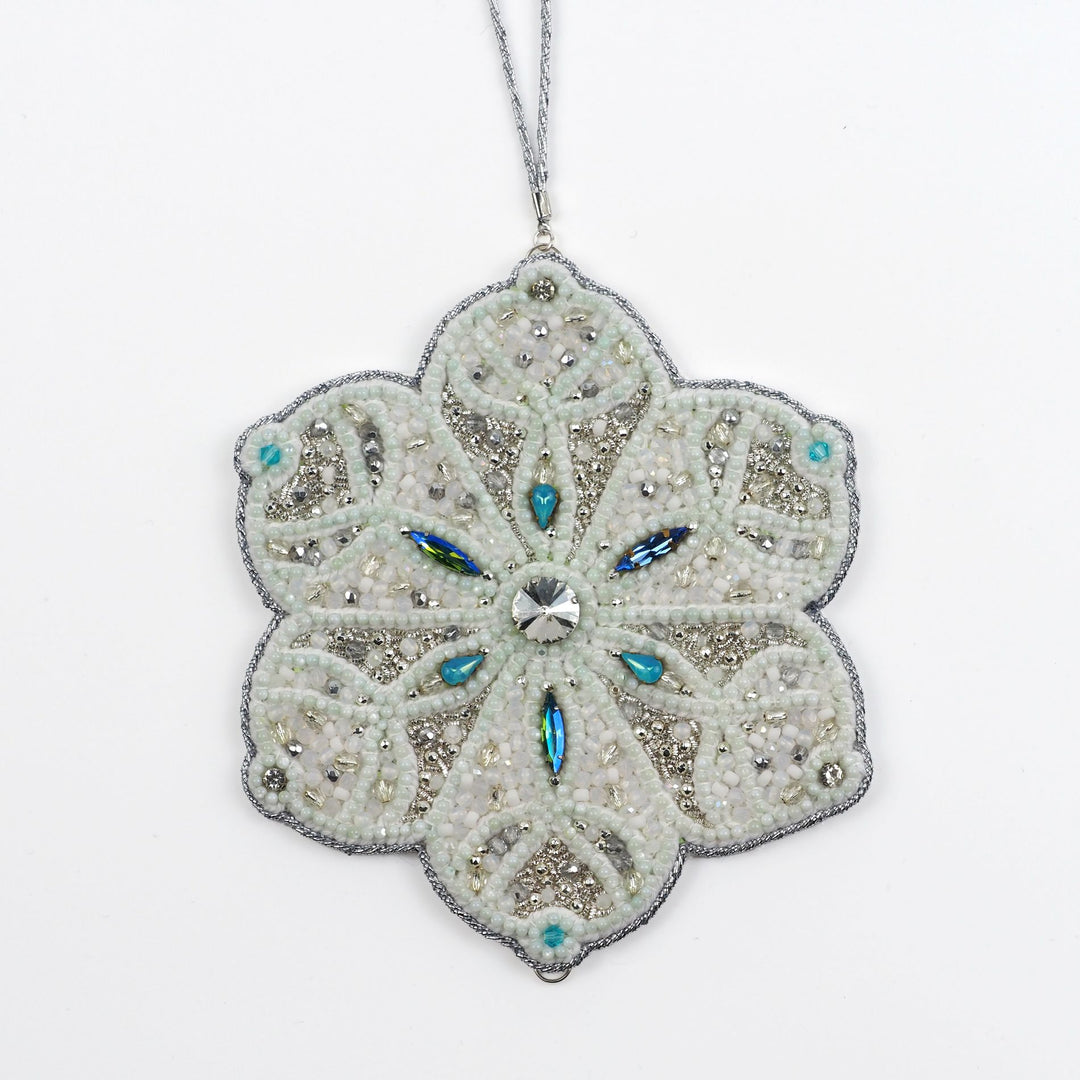 Close-up of the Jewels of Winter Six-Pointed Snowflake Ornament by Ksenia Semirova. Detailed bead and crystal work in white, silver, and turquoise tones, created with the pearl-setting technique and finished with a white leather back.