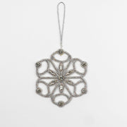 Full view of the Jewels of Winter Six-Pointed Cut-Out Snowflake Ornament by Ksenia Semirova. Handmade with the pearl-setting technique in a lace-like silver design featuring fire-polished glass beads, crystals, and a silver hanging cord.