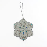 Full view of the Jewels of Winter Six-Pointed Snowflake Ornament by Ksenia Semirova. Hand-embroidered using the pearl-setting technique with white and silver beads, turquoise crystals, and a silver hanging cord.