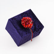 Handmade red dahlia brooch displayed on a dark velvet box, highlighting the intricate beading and limited edition design