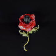 Close-up of a handmade 3D red poppy brooch with sequin petals, velvet-lined back, and embroidered leaves, shown on a black background