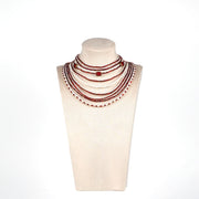 Handmade red and white multi-strand necklace with glass beads, mother of pearl beads, and larger gold-edged round beads, displayed on a mannequin bust