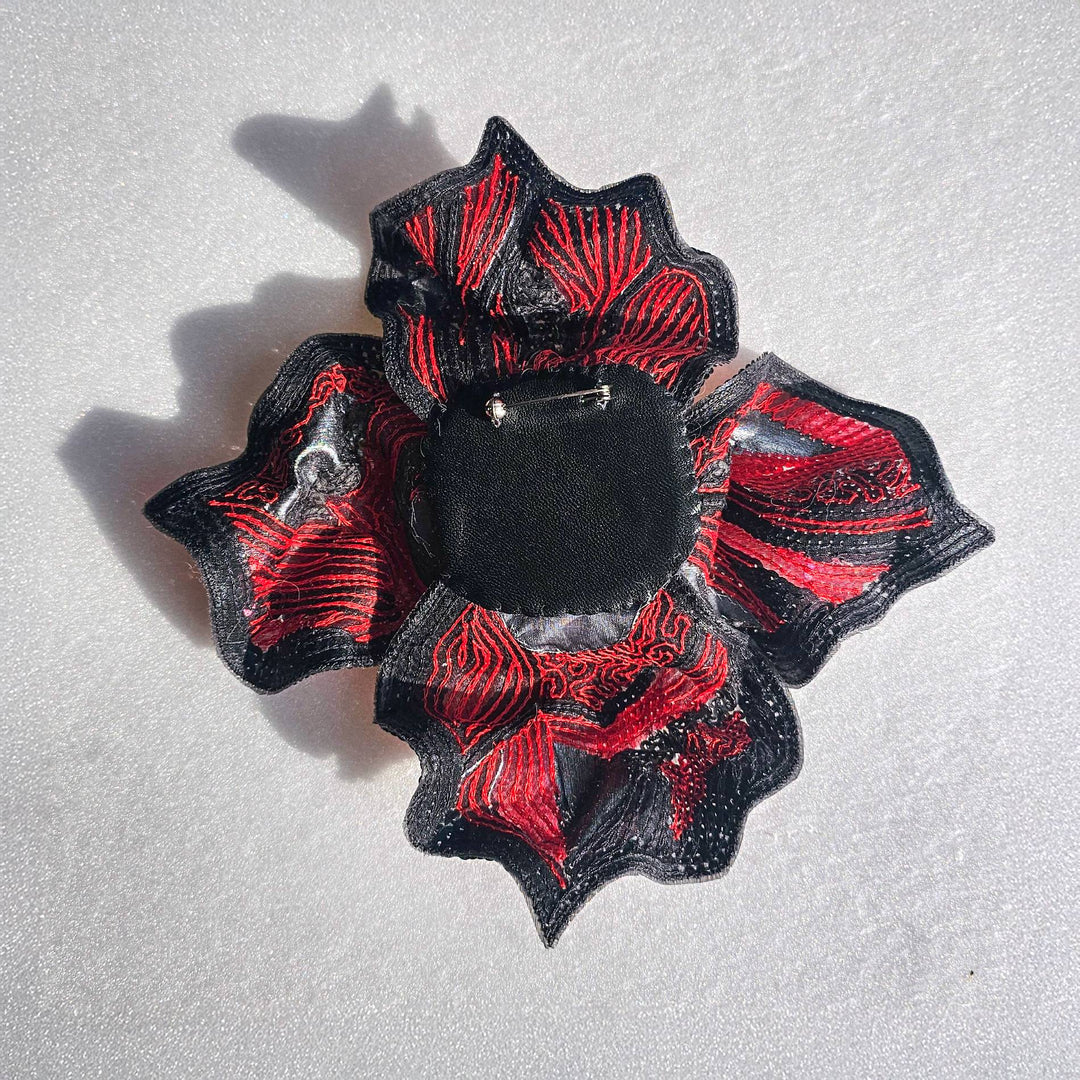 Back view of red and black floral brooch by Ksenia Semirova, showing embroidery details, reinforced backing, and metal pin fastening