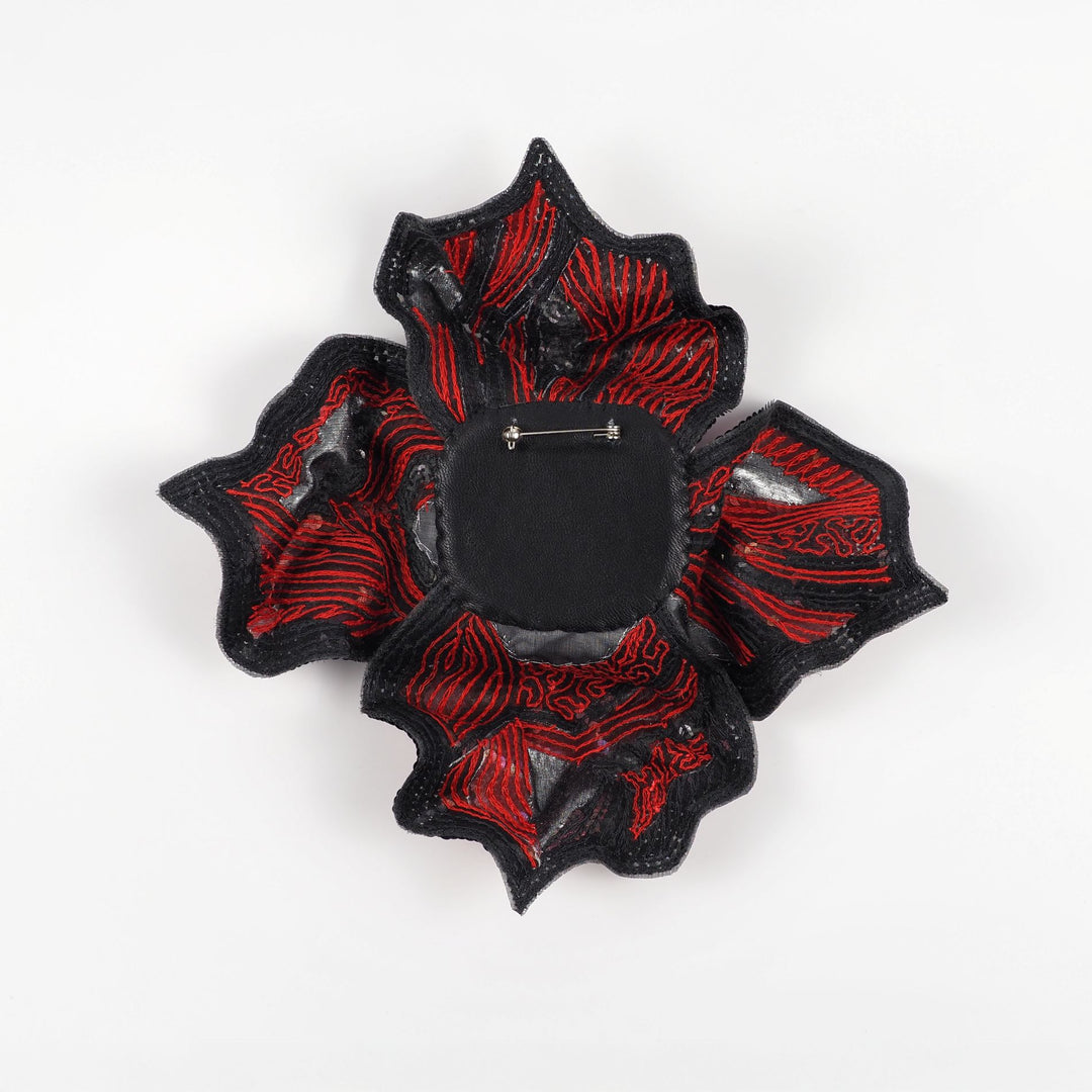 Back view of red and black floral brooch by Ksenia Semirova, showing embroidery details, reinforced backing, and metal pin fastening