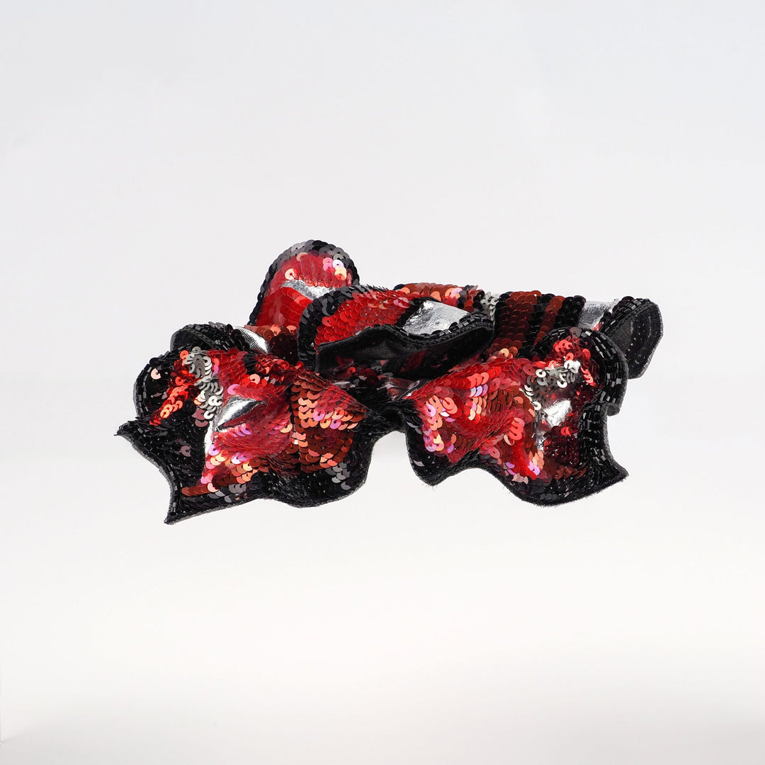 Side view of red and black hand embroidered floral brooch by Ksenia Semirova, showing its sculptural three-dimensional form with sequins and silver highlights.