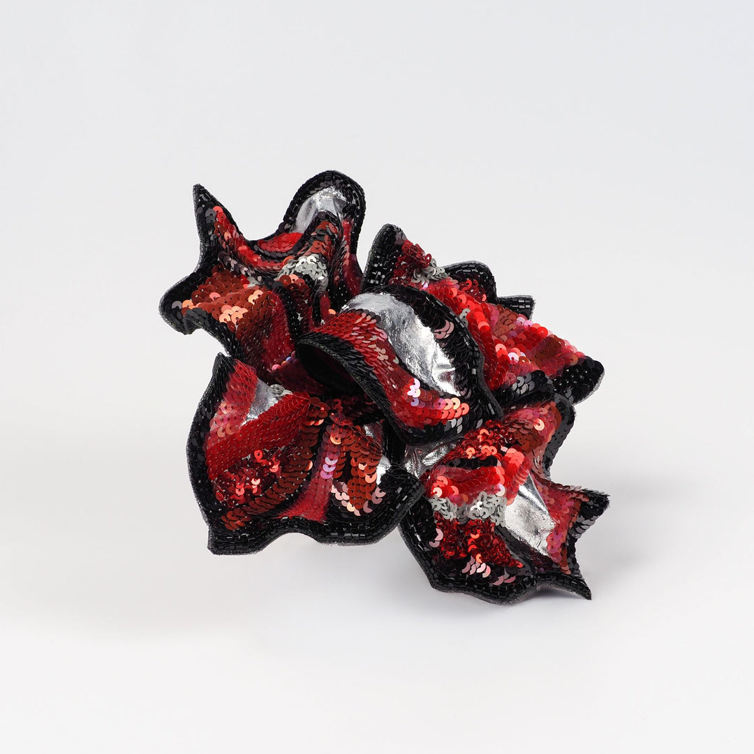 Angled front view of red and black hand embroidered floral brooch with Italian sequins, glass beads, and silver-foil details, handmade by Ksenia Semirova.